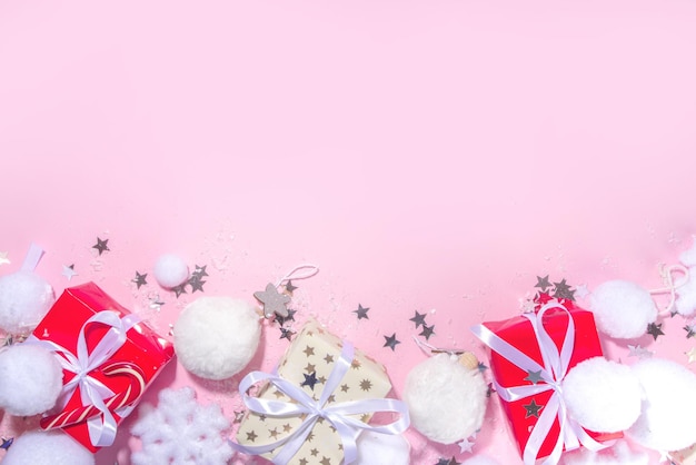 Concetto di Natale soffice. Sfondo festivo di Natale con decorazioni soffici, palla di Natale, scatole regalo, con neve artificiale e stelle lucenti su sfondo di colore rosa copia spazio