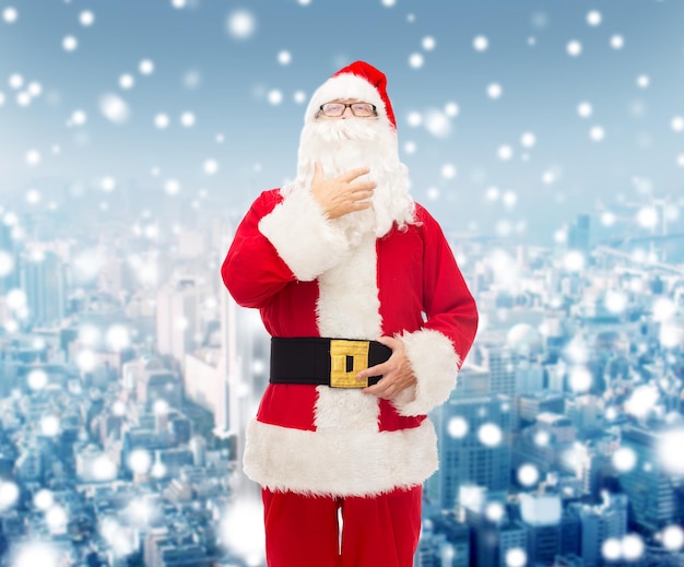 concetto di natale, vacanze e persone - uomo in costume di babbo natale su sfondo di città innevata