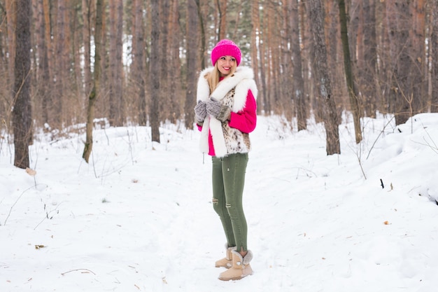 Concetto di natura, moda e persone - giovane donna bionda attraente in posa nel parco invernale.