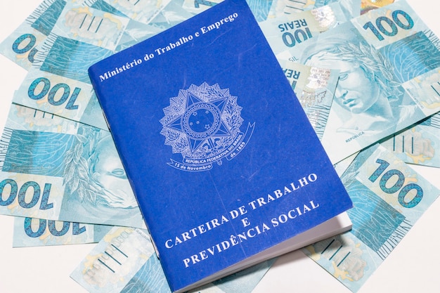 Concetto di occupazione e controllo finanziario con banconote in contanti e portafoglio di lavoro brasiliano.