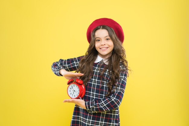 Concetto di ore felici. Calendario e tempi. Ragazza con sveglia. Imposta la sveglia. Orologio rosso della tenuta della bambina del bambino. È ora. Sempre in tempo. Non è mai troppo tardi. Definisci il tuo ritmo di vita.