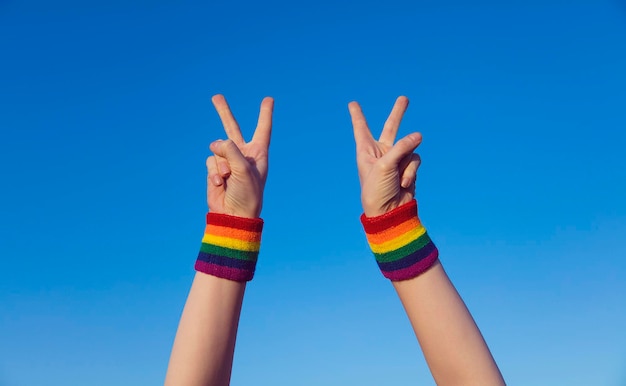 Concetto di orgoglio gay Fare a mano un segno di pace a V con il braccialetto con bandiera arcobaleno LGBT dell'orgoglio gay