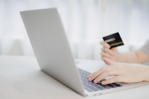 Concetto di pagamento online. Mano che tiene una carta di credito e usa il laptop per lo shopping online.