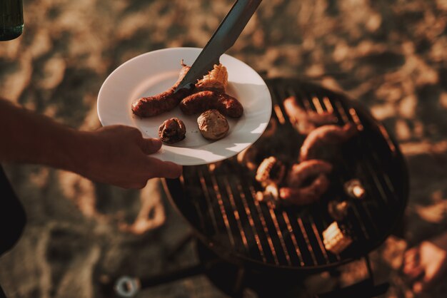 Concetto di partito. Man Grills Barbecue Sausages.