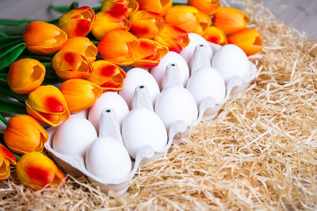 Concetto di Pasqua e primavera primo piano di una scatola con uova e tulipani arancioni