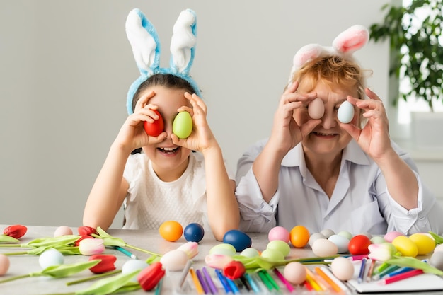 Concetto di Pasqua. La nonna con la nipote tiene le uova di Pasqua a casa.