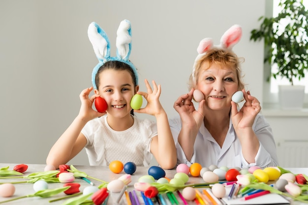 Concetto di Pasqua. La nonna con la nipote tiene le uova di Pasqua a casa.