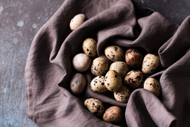 Concetto di Pasqua scuro piatto con uova di quaglia in cartone su panno scuro copia spazio vista dall'alto