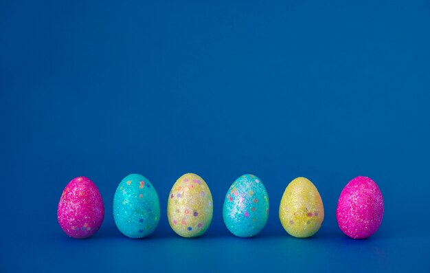 Concetto di pasqua. Uova di Pasqua multicolori su una parete d'avanguardia blu. Layout, primo piano, copia spazio