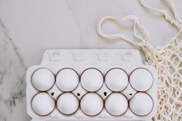 Concetto di Pasqua, uova di pollo piatto e borsa eco su fondo di marmo. Vista dall&#39;alto.