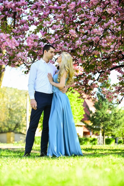 Concetto di passione. Uomo e donna in un giardino fiorito. Le coppie trascorrono del tempo nel giardino dell'albero di primavera. Coppia innamorata sotto il fiore di sakura. Coppia innamorata sotto il fiore di sakura. Storia d'amore. Le persone che amano si abbracciano.