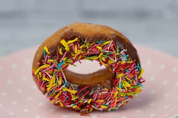 Concetto di pasticceria. Ciambelle con glassa al cioccolato con granelli colorati, su un piatto rosa. vista laterale