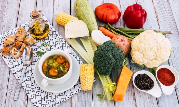 Concetto di pasto sano e dietetico Una zuppa di verdure fatta in casa fresca pronta Verdure crude sul tavolo di legno pepe nero olio d'oliva e crostini