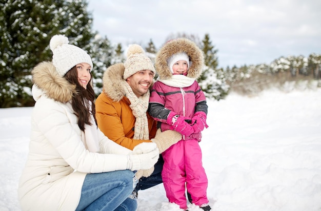 Concetto di paternità, di modo, di stagione e della gente - la famiglia felice con il bambino nell'inverno copre all'aperto