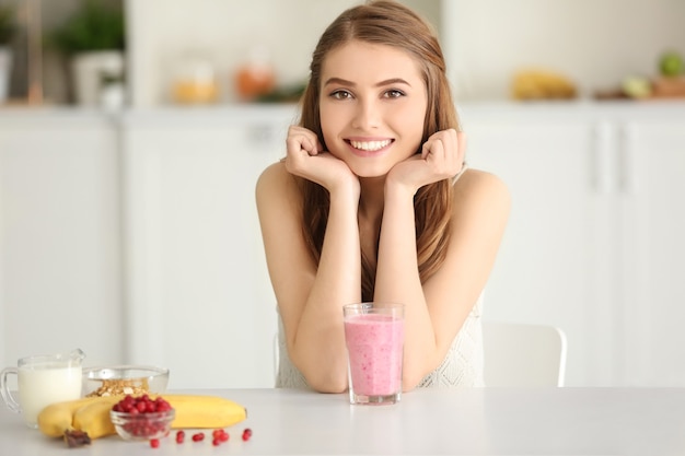 Concetto di perdita di peso. Bella giovane donna con frullato sano e delizioso in cucina