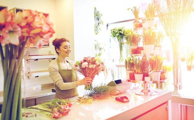 concetto di persone, affari, vendita e floristica - donna fiorista sorridente felice che fa mazzo al negozio di fiori