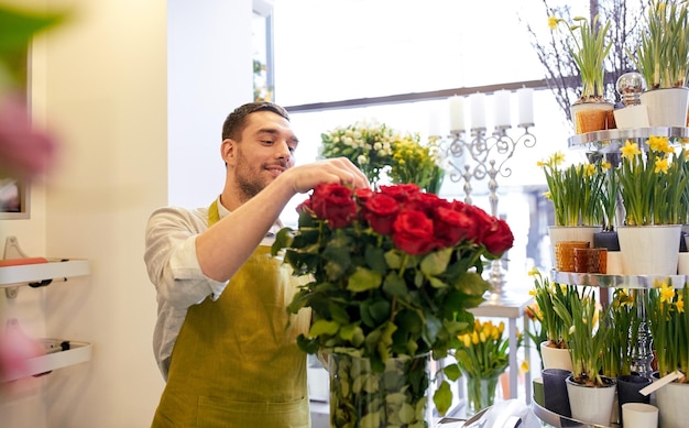 concetto di persone, affari, vendita e floristica - felice fiorista sorridente con rose rosse al negozio di fiori