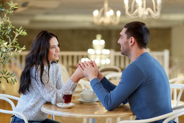 concetto di persone, amore, romanticismo e incontri - coppia felice che beve tè e si tiene per mano al bar o al ristorante