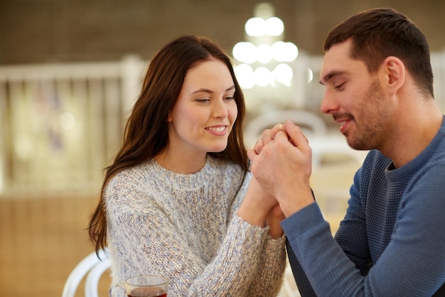 concetto di persone, amore, romanticismo e incontri - coppia felice che beve tè e si tiene per mano al bar o al ristorante