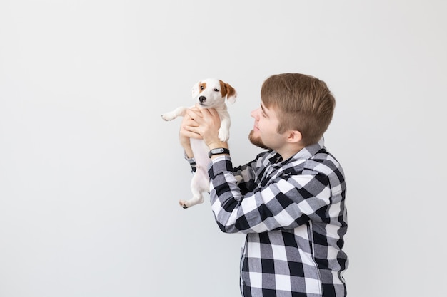 concetto di persone, animali domestici e animali - giovane azienda jack russell terrier cucciolo su superficie bianca