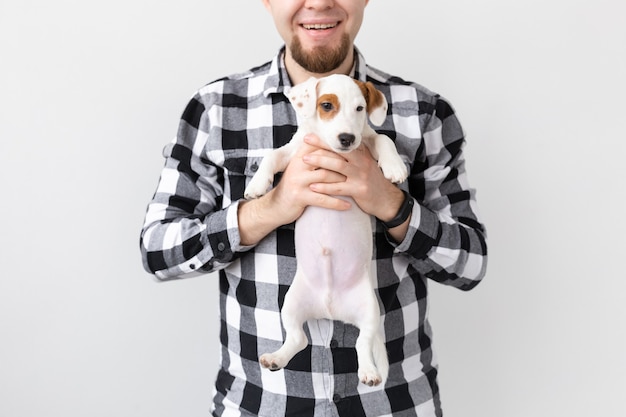 Concetto di persone, animali domestici e cani - primo piano di un uomo che abbraccia un cucciolo divertente su sfondo bianco