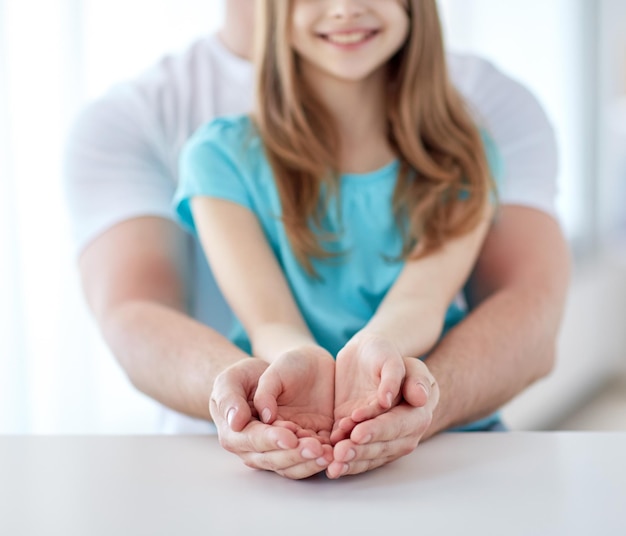 concetto di persone, carità, famiglia e pubblicità - primo piano di padre e ragazza che tengono qualcosa in mani vuote a coppa a casa