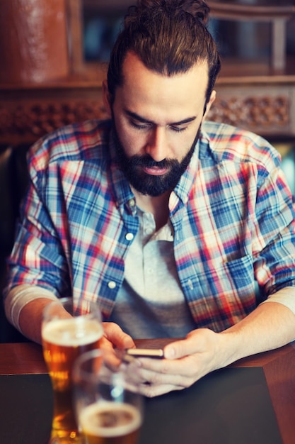 concetto di persone e tecnologia - uomo con smartphone che beve birra e legge un messaggio al bar