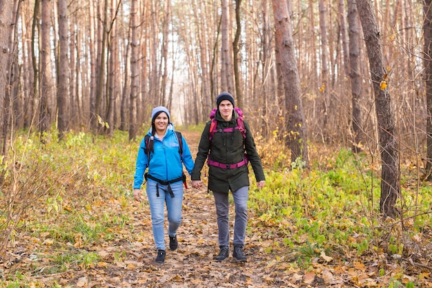 Concetto di persone, escursione, turismo e natura - escursionismo turistico di coppia nella foresta di autunno.