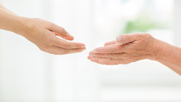 concetto di persone, età, famiglia, cura e supporto - primo piano di una donna anziana e una giovane donna che si allungano le mani