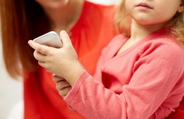 concetto di persone, famiglia e tecnologia - primo piano di donna e bambina con smartphone