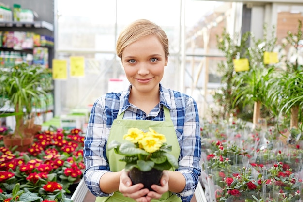 concetto di persone, giardinaggio e professione - donna felice o giardiniere che tiene fiori in serra o negozio