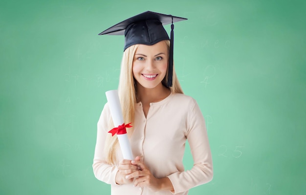 concetto di persone, istruzione, scuola superiore e laurea - ragazza studentessa felice in berretto da scapolo con diploma su sfondo verde lavagna