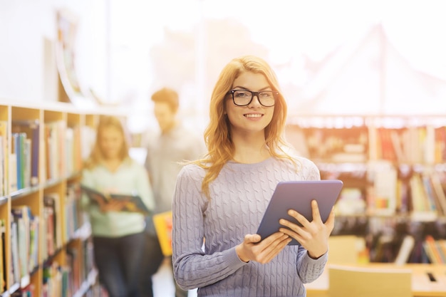 concetto di persone, istruzione, tecnologia e scuola - studentessa felice o donna con computer tablet pc in biblioteca