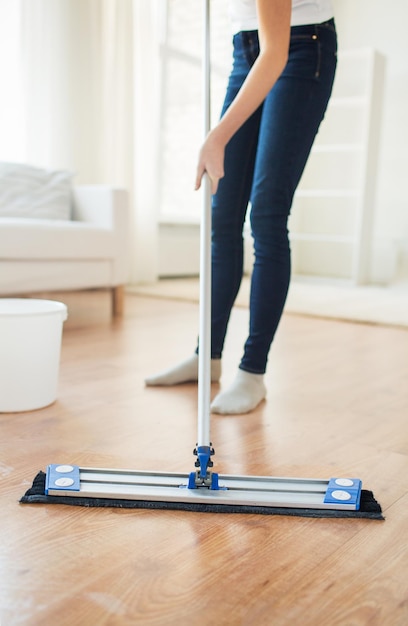 concetto di persone, lavori domestici e pulizie - primo piano delle gambe della donna con il pavimento per la pulizia del mocio a casa