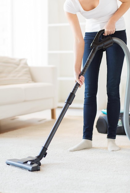 concetto di persone, lavori domestici e pulizie - primo piano di una donna con un tappeto per la pulizia dell'aspirapolvere a casa