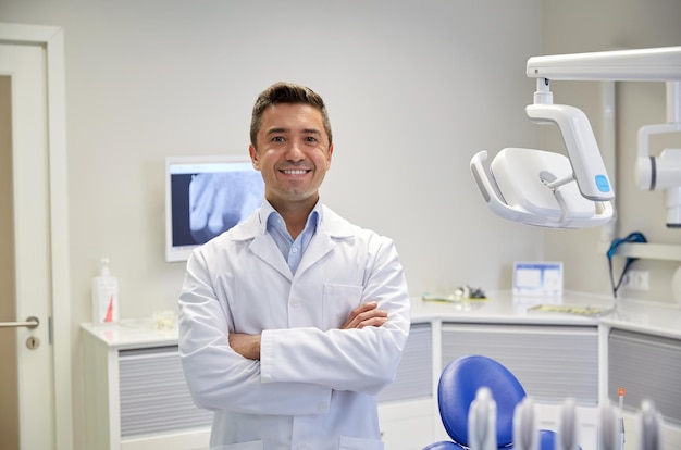 concetto di persone, medicina, stomatologia e assistenza sanitaria - dentista maschio di mezza età felice in camice bianco presso l'ufficio della clinica dentale