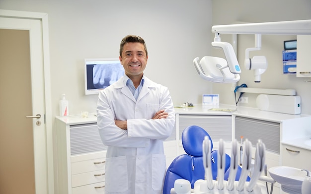 concetto di persone, medicina, stomatologia e assistenza sanitaria - dentista maschio di mezza età felice in camice bianco presso l'ufficio della clinica dentale