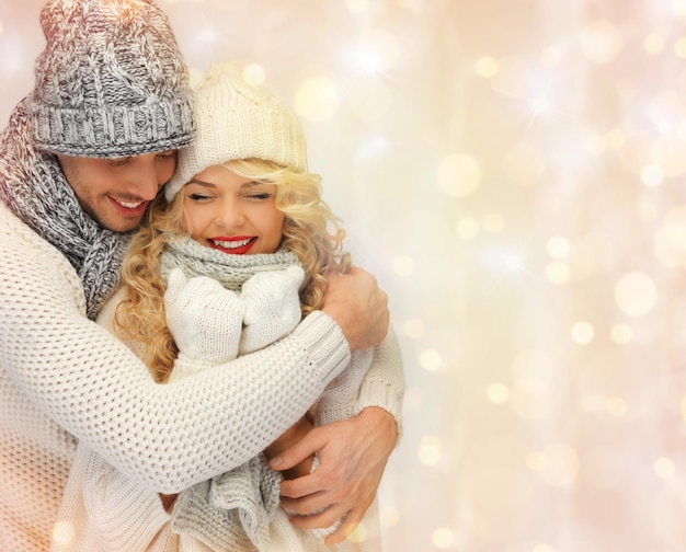 concetto di persone, natale, vacanze e capodanno - coppia di famiglia felice in abiti invernali che abbracciano sullo sfondo delle luci delle vacanze