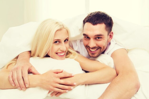 concetto di persone, riposo, relazioni e felicità - coppia felice a letto a casa