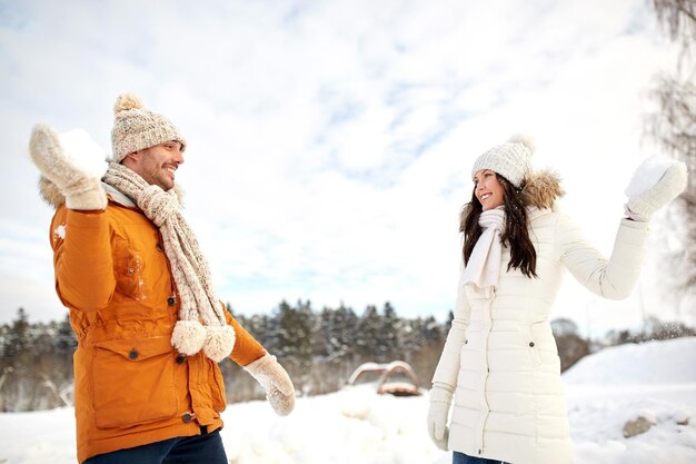 concetto di persone, stagione, amore e tempo libero - coppia felice che gioca a palle di neve in inverno