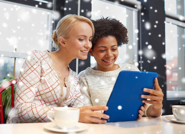 concetto di persone, tempo libero, amicizia e tecnologia - giovani donne felici con computer tablet pc che bevono tè o caffè al bar sopra l'effetto neve