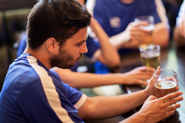 concetto di persone, tempo libero, calcio e sport - tifosi di calcio infelici o amici con birra al bar o pub