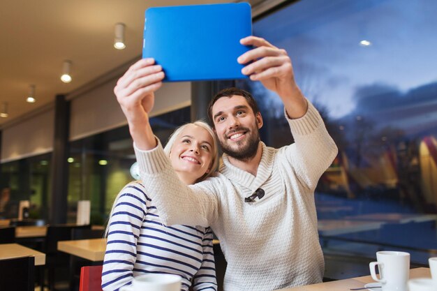 concetto di persone, tempo libero, comunicazione, mangiare e bere - coppia felice con computer tablet pc prendendo selfie al bar