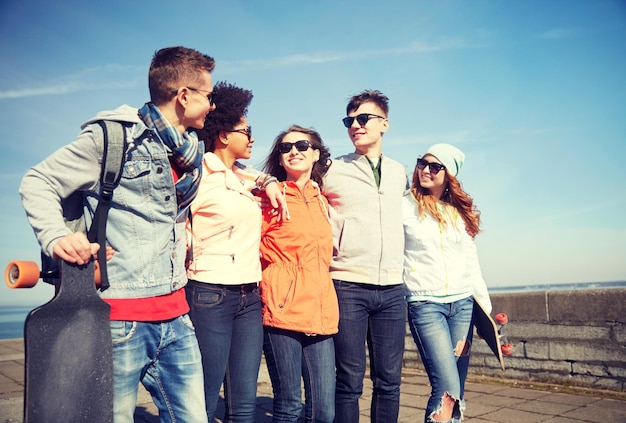 concetto di persone, tempo libero e sport - gruppo di amici adolescenti felici con longboard che parlano sulla strada della città