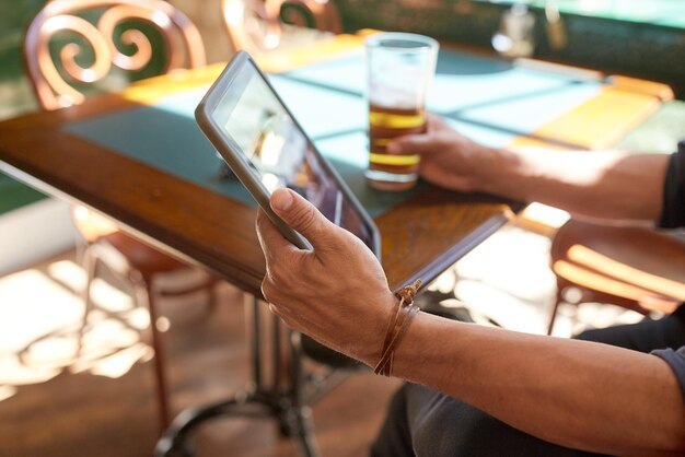 concetto di persone, tempo libero e tecnologia - primo piano dell'uomo con il computer tablet pc che beve birra al bar o al pub