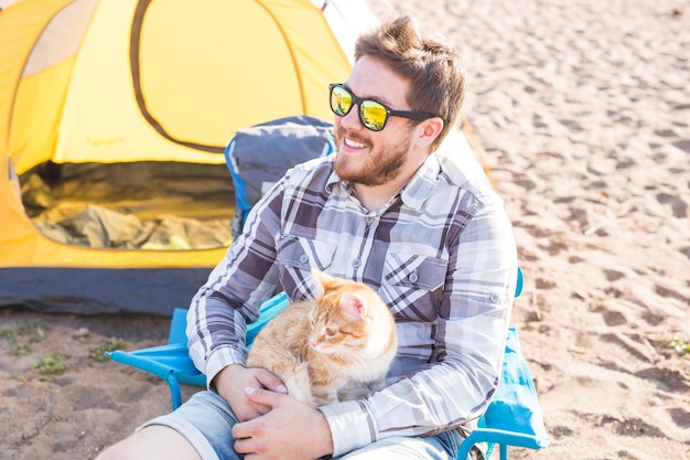 Concetto di persone, turismo e natura - Uomo che tiene gatto sulla natura