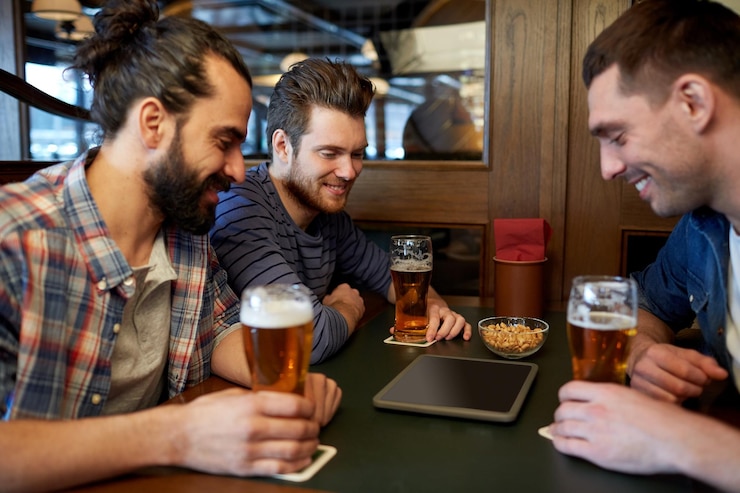 Foto concetto di persone, uomini, tempo libero, amicizia e tecnologia - amici maschi felici con computer tablet pc che bevono birra alla spina al bar o al pub