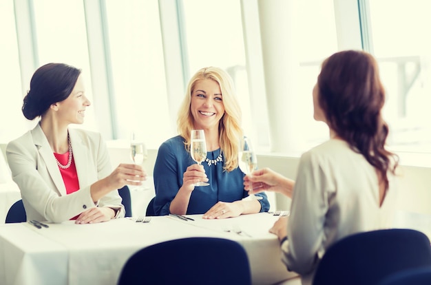 concetto di persone, vacanze, celebrazione e stile di vita - donne felici che bevono champagne al ristorante