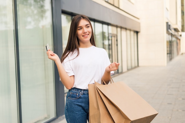 Concetto di persone, vendita e consumismo - close up di donna felice con borse della spesa e carta di credito sulla strada cittadina