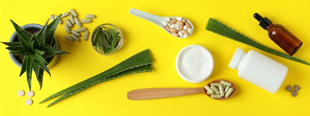 Concetto di pillole di erbe e cosmetici con aloe su sfondo giallo